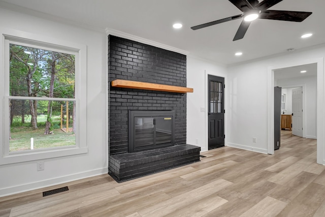 unfurnished living room featuring crown molding, ceiling fan, light wood-type flooring, and a fireplace