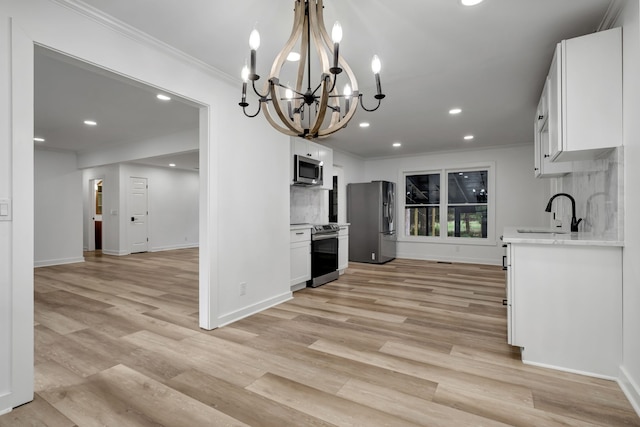 kitchen with white cabinetry, a chandelier, decorative light fixtures, sink, and appliances with stainless steel finishes