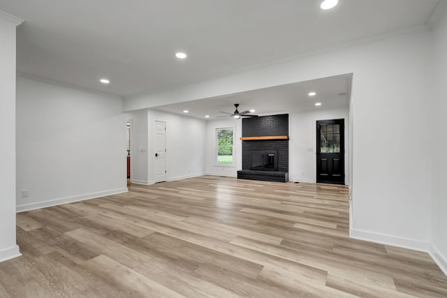 unfurnished living room featuring a fireplace, crown molding, light hardwood / wood-style flooring, and ceiling fan