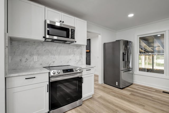 kitchen with white cabinets, backsplash, appliances with stainless steel finishes, light stone counters, and light hardwood / wood-style floors