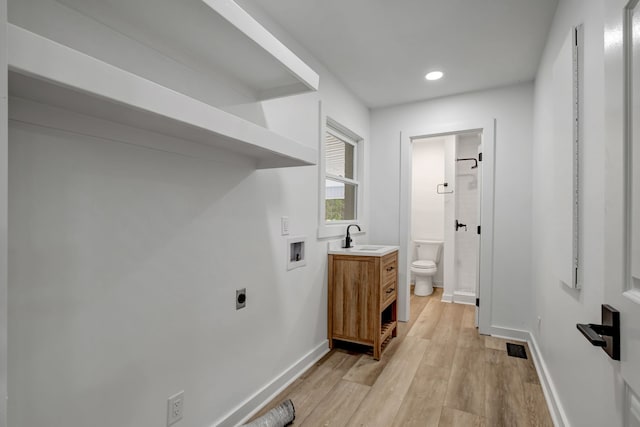 clothes washing area featuring washer hookup, hookup for an electric dryer, sink, and light hardwood / wood-style flooring