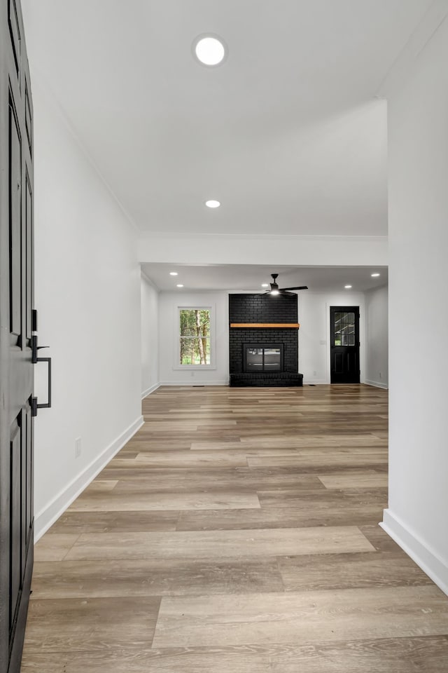 unfurnished living room with light wood-type flooring, ceiling fan, and ornamental molding