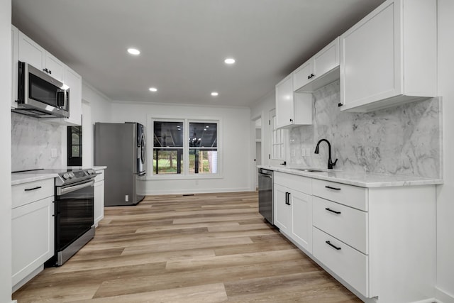 kitchen with light hardwood / wood-style flooring, backsplash, appliances with stainless steel finishes, sink, and white cabinets