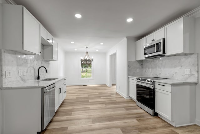 kitchen with light hardwood / wood-style flooring, backsplash, stainless steel appliances, sink, and a chandelier