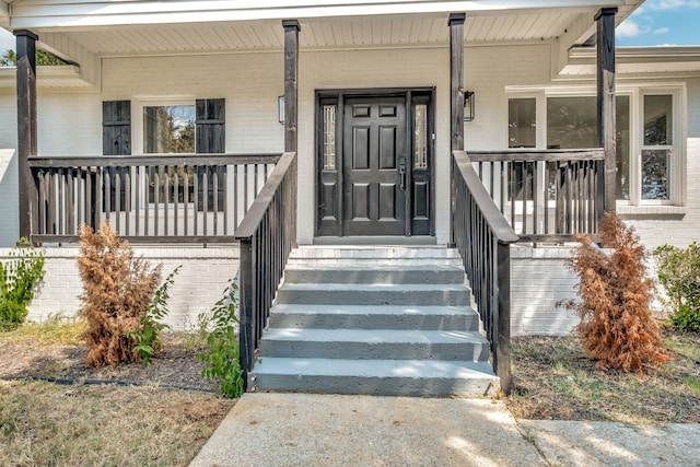 view of exterior entry featuring covered porch