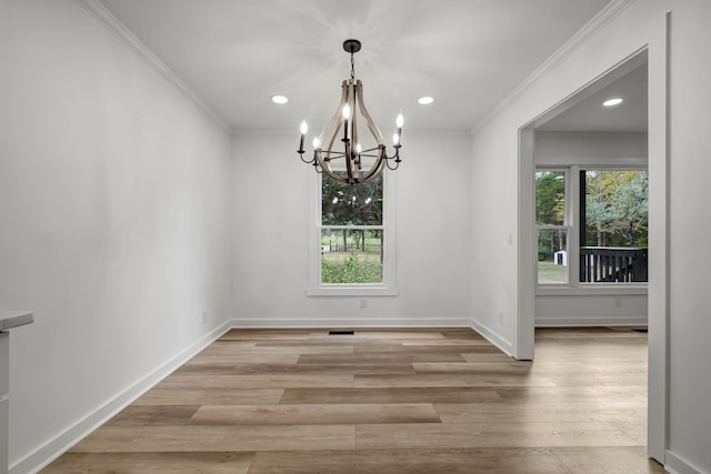 unfurnished dining area featuring light wood-type flooring, ornamental molding, a wealth of natural light, and a chandelier