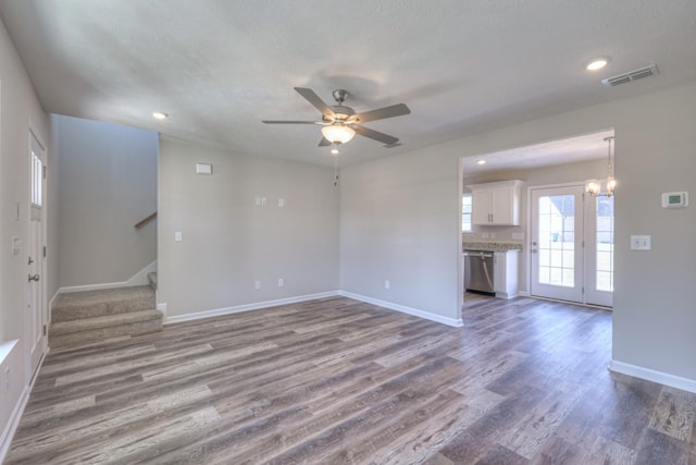 unfurnished living room with hardwood / wood-style floors, ceiling fan with notable chandelier, and a textured ceiling