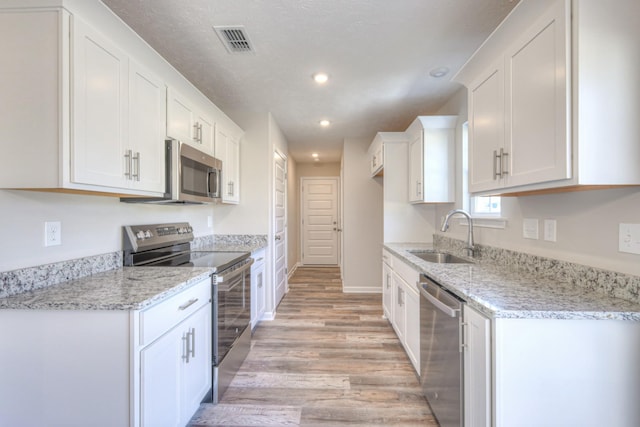 kitchen featuring stainless steel appliances, light stone countertops, sink, and white cabinets