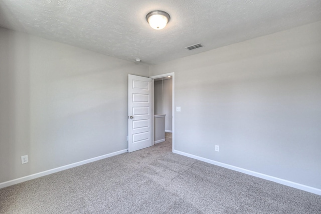 carpeted empty room with a textured ceiling