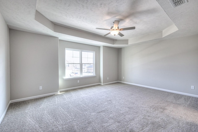 carpeted spare room featuring a raised ceiling, ceiling fan, and a textured ceiling