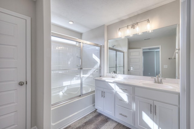 bathroom with enclosed tub / shower combo, vanity, and hardwood / wood-style floors