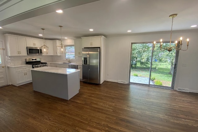 kitchen with appliances with stainless steel finishes, decorative light fixtures, sink, and dark hardwood / wood-style floors