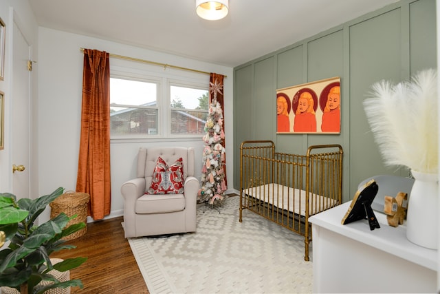 bedroom with a nursery area and dark hardwood / wood-style floors