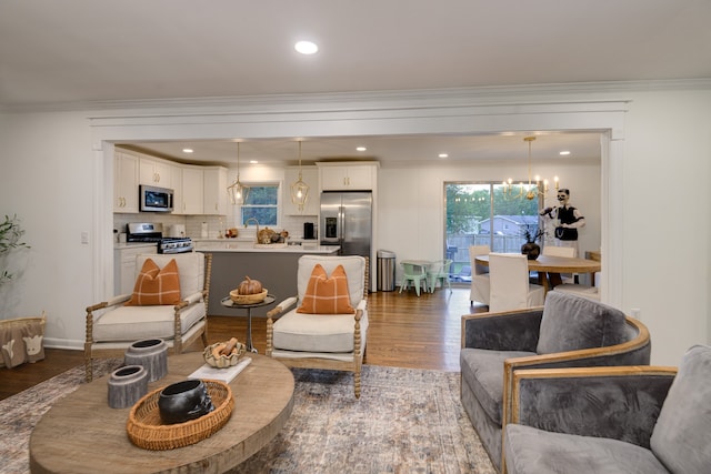 living room featuring crown molding, hardwood / wood-style floors, sink, and a notable chandelier