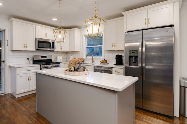 kitchen with white cabinets, a center island, decorative light fixtures, stainless steel appliances, and dark wood-type flooring