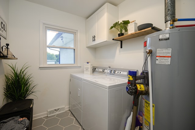 clothes washing area featuring cabinets, water heater, and washing machine and clothes dryer