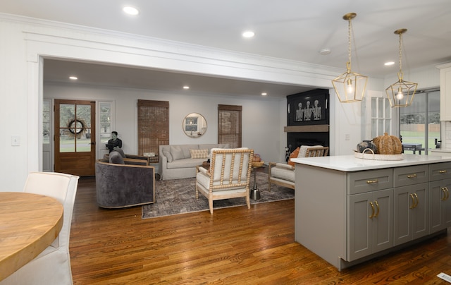 kitchen featuring gray cabinetry, decorative light fixtures, a large fireplace, dark wood-type flooring, and ornamental molding