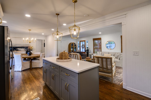 kitchen featuring stainless steel refrigerator, ornamental molding, dark hardwood / wood-style flooring, a kitchen island, and hanging light fixtures