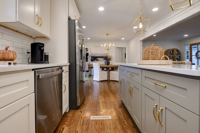 kitchen featuring backsplash, decorative light fixtures, stainless steel appliances, dark hardwood / wood-style floors, and ornamental molding