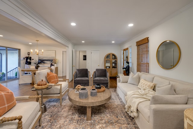 living room featuring wood-type flooring, a notable chandelier, and ornamental molding