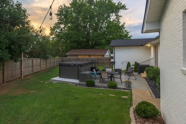 yard at dusk featuring a patio and a hot tub