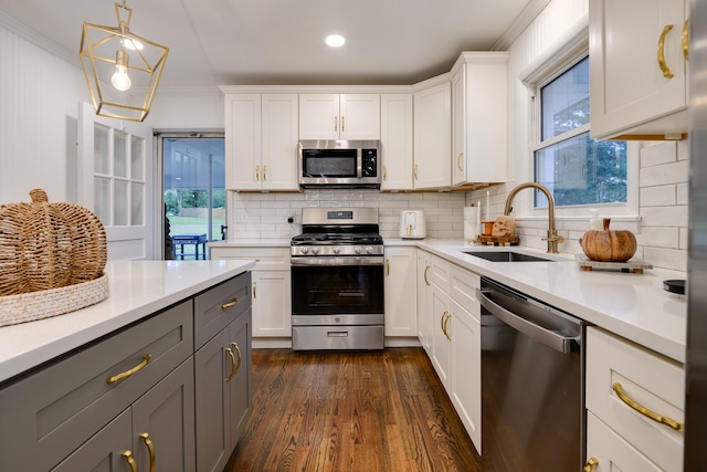 kitchen with gray cabinets, stainless steel appliances, sink, hanging light fixtures, and white cabinets