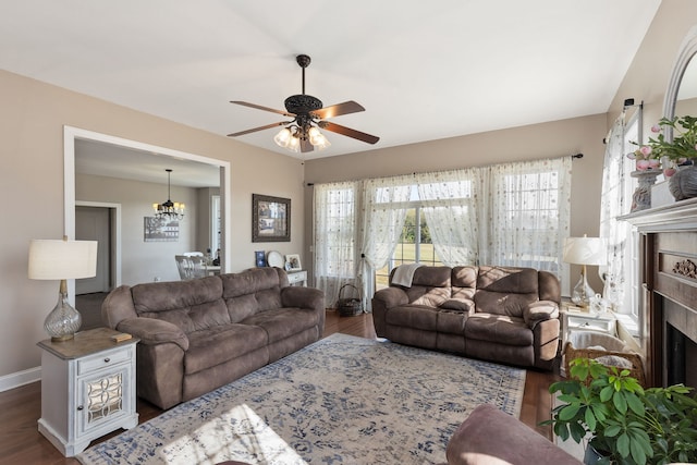 living room featuring ceiling fan with notable chandelier, dark wood-type flooring, and a high end fireplace