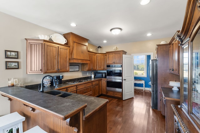 kitchen with dark hardwood / wood-style floors, a breakfast bar area, sink, kitchen peninsula, and stainless steel appliances