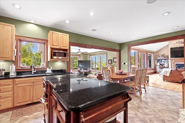 kitchen featuring a kitchen island, light hardwood / wood-style floors, sink, ceiling fan, and stainless steel microwave