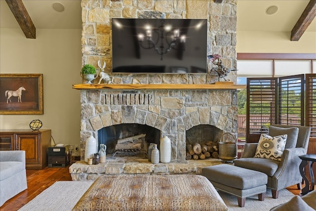 living room featuring beamed ceiling, hardwood / wood-style floors, and a stone fireplace