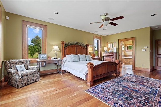 bedroom with multiple windows, wood-type flooring, connected bathroom, and ceiling fan