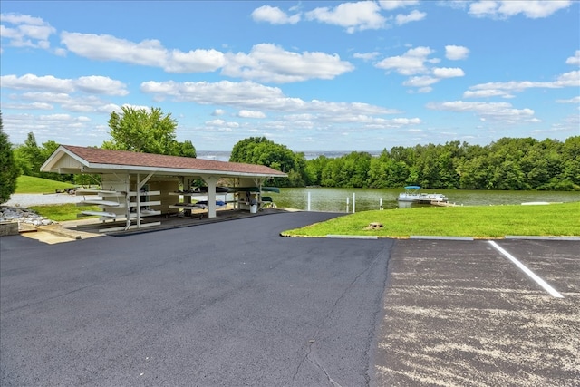 view of parking / parking lot featuring a water view and a lawn