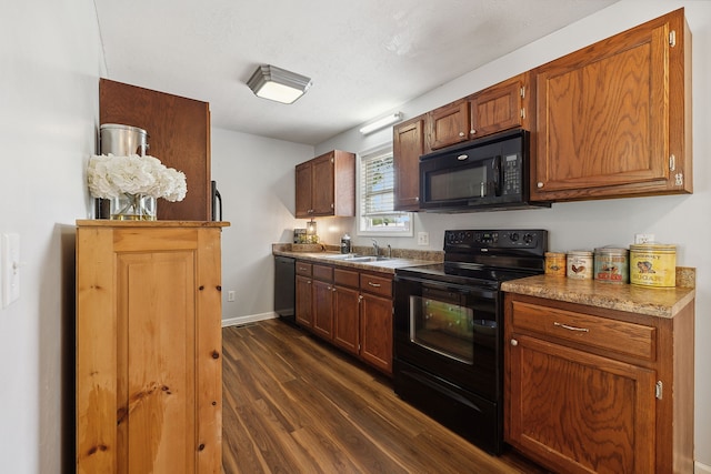 kitchen with a textured ceiling, black appliances, sink, and dark hardwood / wood-style flooring