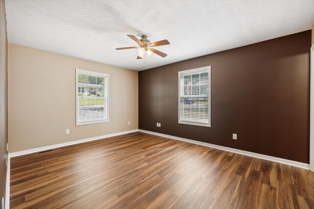 empty room with a textured ceiling, dark wood-type flooring, and ceiling fan