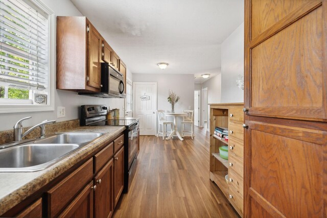 kitchen with appliances with stainless steel finishes, dark hardwood / wood-style flooring, and sink