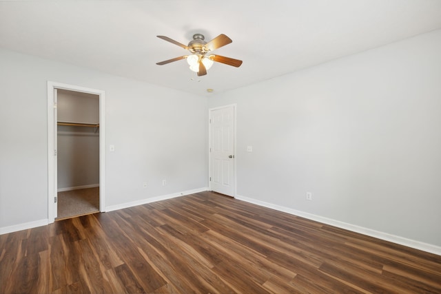 unfurnished bedroom with dark wood-type flooring, a walk in closet, ceiling fan, and a closet