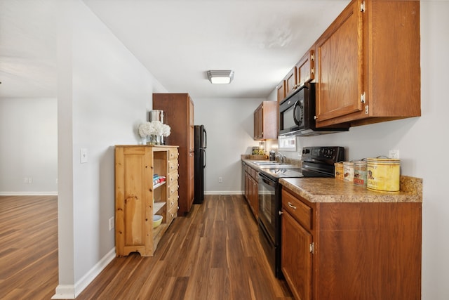 kitchen with black appliances and dark hardwood / wood-style flooring