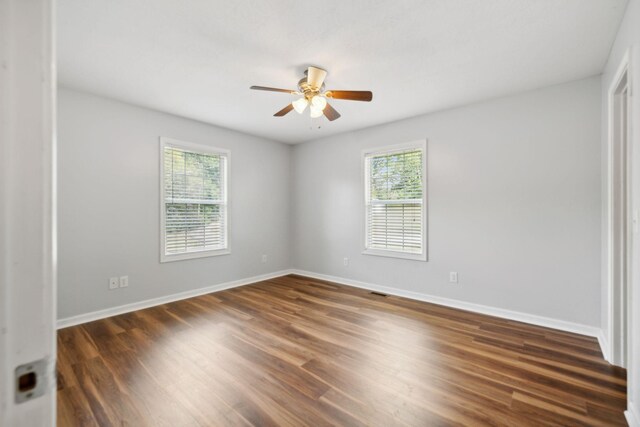 empty room with plenty of natural light, ceiling fan, and dark hardwood / wood-style flooring