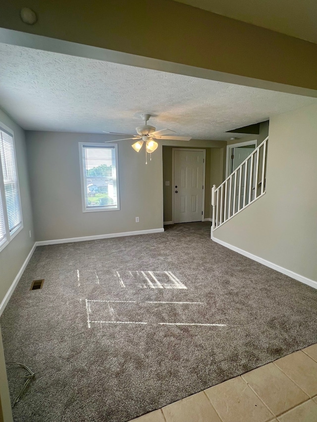 carpeted empty room with ceiling fan and a textured ceiling