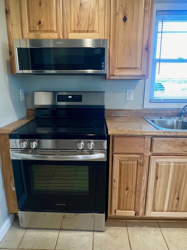 kitchen featuring appliances with stainless steel finishes, light tile patterned floors, and sink