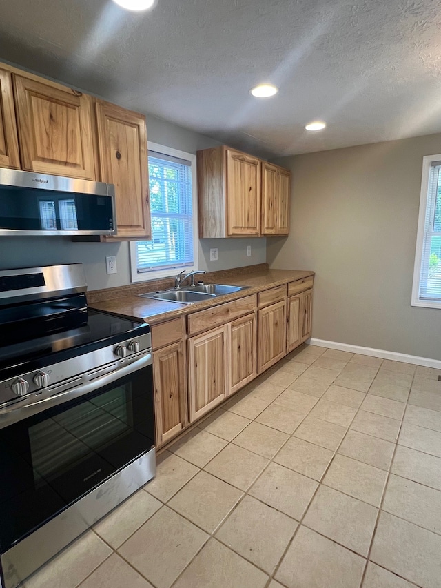 kitchen featuring a textured ceiling, plenty of natural light, stainless steel appliances, and sink