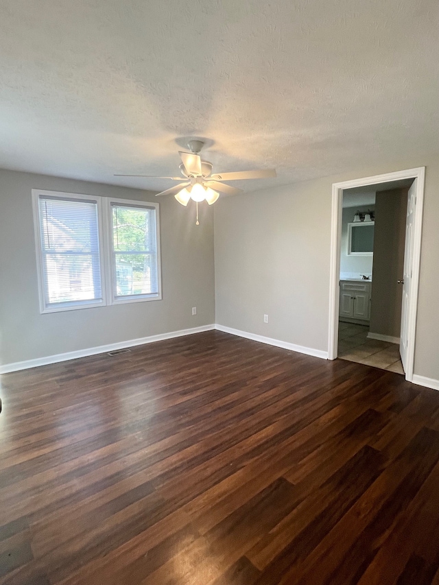 unfurnished bedroom with ceiling fan, connected bathroom, dark hardwood / wood-style flooring, and a textured ceiling