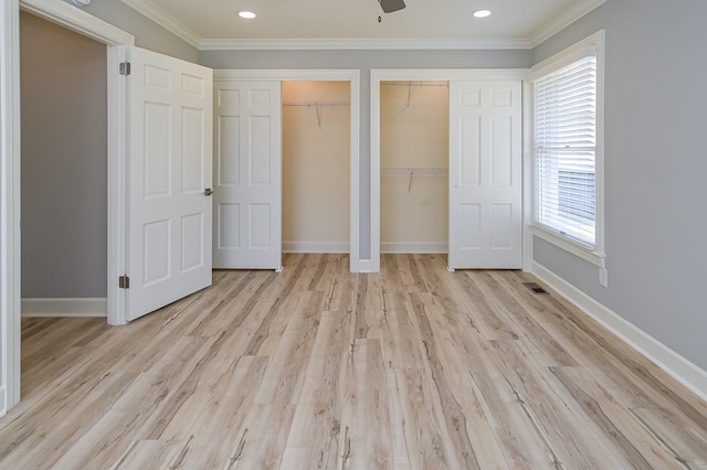 unfurnished bedroom with light hardwood / wood-style flooring, ceiling fan, ornamental molding, and multiple closets