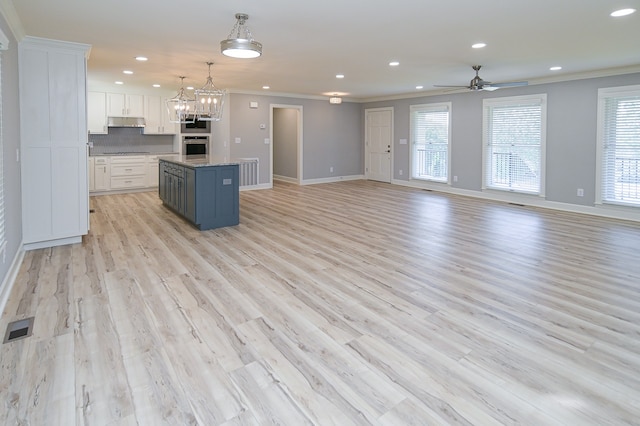 kitchen with ceiling fan with notable chandelier, decorative light fixtures, light hardwood / wood-style floors, a center island, and white cabinetry