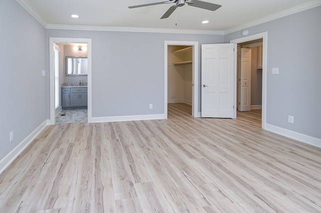 unfurnished bedroom with ensuite bathroom, ceiling fan, a closet, a spacious closet, and light hardwood / wood-style floors