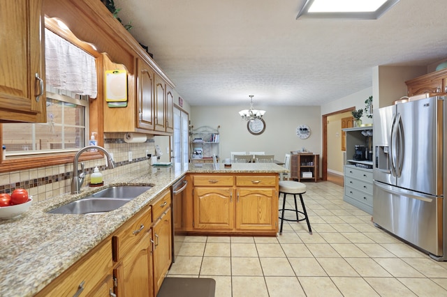 kitchen featuring backsplash, hanging light fixtures, stainless steel appliances, sink, and kitchen peninsula