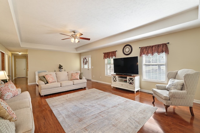 living room with a tray ceiling, ceiling fan, and hardwood / wood-style flooring