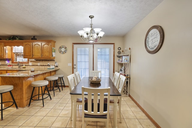 dining area featuring light tile patterned floors, a chandelier, a textured ceiling, and sink