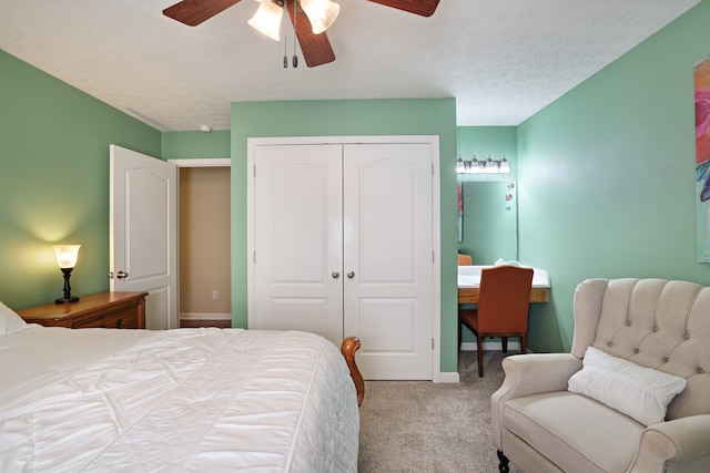 bedroom featuring a textured ceiling, light colored carpet, ceiling fan, and a closet