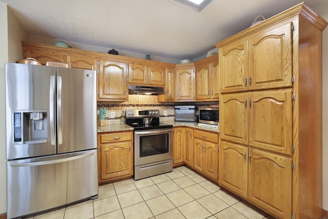 kitchen with stainless steel appliances, light tile patterned floors, decorative backsplash, and light stone countertops